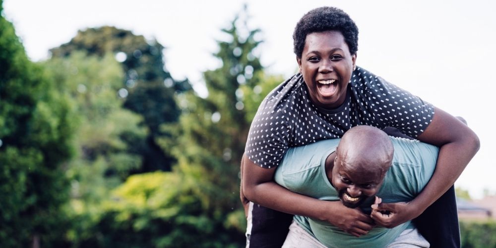 Teen boy jumping on his dad's back.